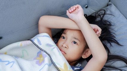 Illness child, feeling sad and freezing. Little girl wrapped in a blanket.