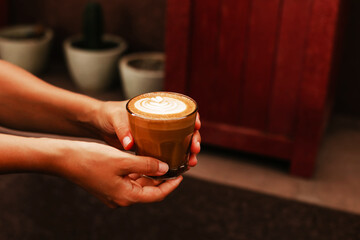 Female hands holding a double cappuccino. A stylish concept for a coffee shop. Woman came for a coffee break in a cafe - obrazy, fototapety, plakaty