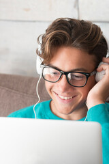 Young and cheerful happy teenager in video conference chat on laptop computer at home - lockdown or...