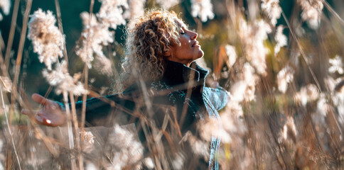 One happy and free woman outstretching arms in golden field of high grass. Concept of healthy lifestyle and wellbeing. Joyful people in outdoor leisure activity. Nature lover female lady enjoying life