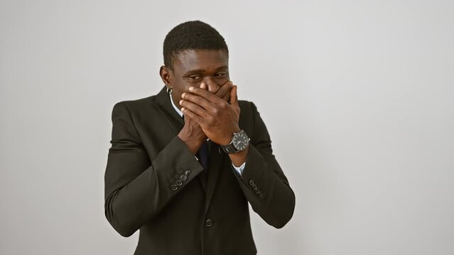 Shocked african american man in suit covering mouth with hand, standing against isolated white background. a secret mistake leaves him embarrassed