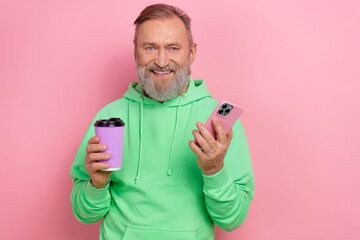 Photo of positive good mood guy dressed green hoodie enjoying coffee chatting instagram twitter telegram facebook isolated pink color background