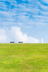 Garden bench with Green meadows with blue sky and clouds background, Landscape view of green grass on slope Scenic panoramic view on a beautiful sunny day,japanese picture concept.