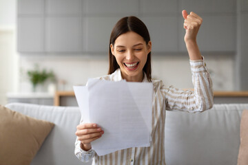 Ecstatic young woman celebrating good news with papers