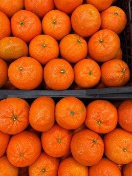 Boxes with Orange mandarins laid in rows in a supermarket or local market fruit crate. Top view, flat lay