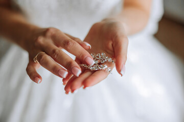 Elegant bride holding silver earrings. Tender hands with jewelry. Young bride puts on her wedding...