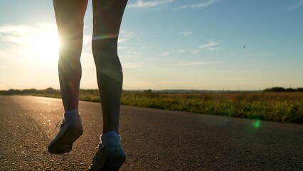 silhouette sports girl running along road sunset, legs close-up, urban marathon runner crossing...
