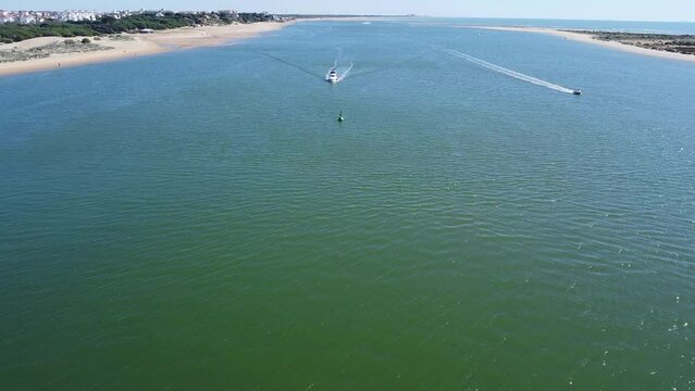 Aerial drone view of a motor boat navigating in the Piedras river between the El Portil beach village and La Flecha sand bank