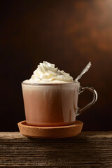 Hot chocolate with whipped cream in a glass mug.