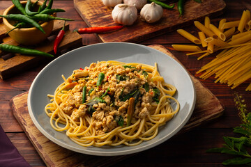 Stir fried spicy spaghetti with minced chicken breast and basil leaves in white plate,Spicy pasta Pad Kra Pao.Healthy Thai fusion food - obrazy, fototapety, plakaty