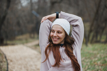 Woman Wearing a White Beanie Stretches Her Arms in a Winter Park