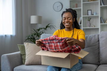 Young woman taking a checkered shirt from the box and smiling