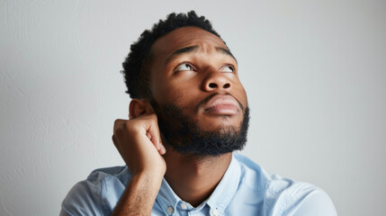 Obraz premium A contemplative man with a hand on his chin looking away thoughtfully.