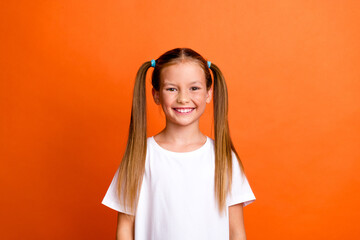 Photo portrait of charming little girl toothy smile cheerful dressed stylish white clothes isolated on orange color background
