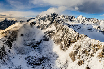Bird's eye view from drone of snow mountain ridge and peak with cloud at sunset time at Dafeng base camp on the Siguniang Shan mountain in Changping Gou National Parks ,Rilong,Chengdu, China