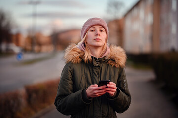 Young Woman Using Smartphone on Urban Street at Sunset