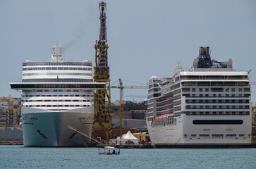 Modern cruise ship cruiseship liner maintenance repair modernization refurbishment overhaul dry docked by Maltese shipyard in Valletta, Malta with dock and cranes