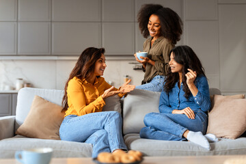 Multiethnic women share stories sitting with cups of tea indoors