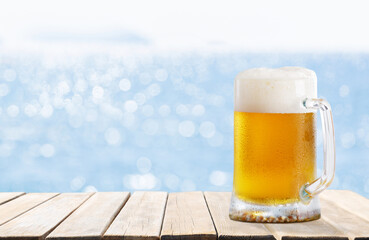 mug of beer on wooden table on sea background