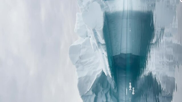 A huge high breakaway glacier is passing by in the southern ocean off the coast of Antarctica, the Antarctic Peninsula, the Southern Circle, azure water, cloudy weather