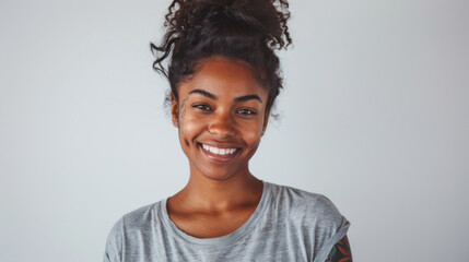 A cheerful woman with red hair tied in a bun, laughing joyfully in a casual grey t-shirt, her freckles and bright expression conveying happiness. - obrazy, fototapety, plakaty