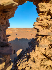 The perspective from a gap in a stone wall unveils the remnants of the Ksar of Ighzer, featuring...