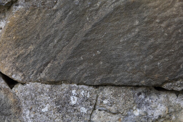 background of dark gray stone wall in cracks and chips