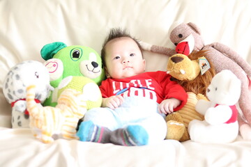 a baby sitting on a couch surrounded by stuffed animals