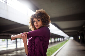Young woman stretching before exercising and jogging in a parking lot