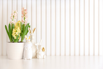 Easter rabbits figurines with pot of hyacinths on white background. Easter celebration concept....