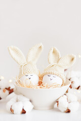 Fototapeta na wymiar Easter eggs in crochet knitted hats with rabbit ears in nest. Easter celebration concept