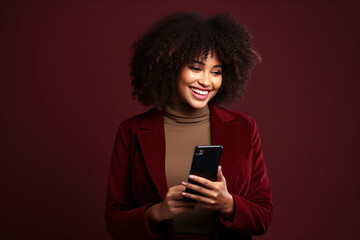 Fototapeta na wymiar Happy African American woman with phone on Burgundy studio background