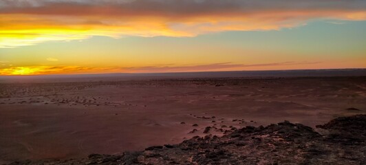 Obraz premium Panoramic sunset view from Timimoun, Algeria, overlooking the red sand desert and canyons from a hilltop.