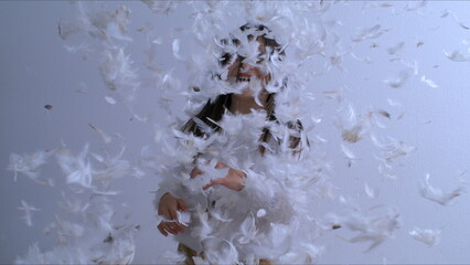 One carefree little girl throwing feathers in the air in super slow motion at 1000 fps. Childhood happiness moment of child covered in plumage