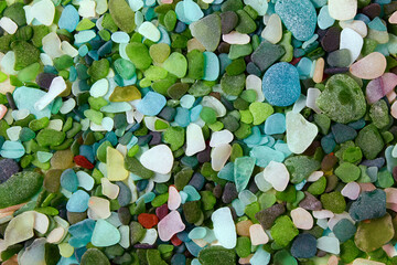 Multi-colored background from sea-polished glass shards of bottles. Glass beach