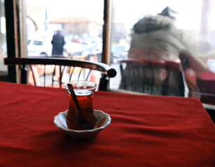 A glass of Turkish tea on the table with red cloth.