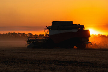 Combine harvester on the field at sunset