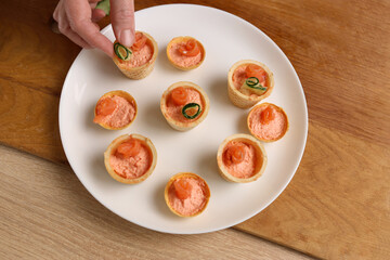Canapes with pate, salmon and cucumber are being prepared.