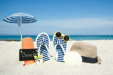 A Beach summer holiday banner background. Flip-flops and hat with a board and ball on the sand near...