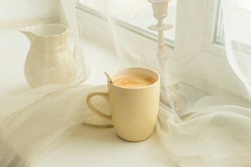 Fototapeta na wymiar Close up for mug of coffee on a white table near a window