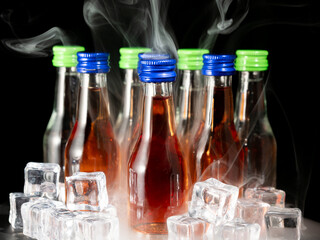 Small bottles of alcoholic drinks in ice cubes. Bottles with alcohol close-up.