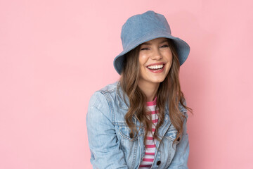 Beautiful girl in a denim hat and jacket on a pink background.