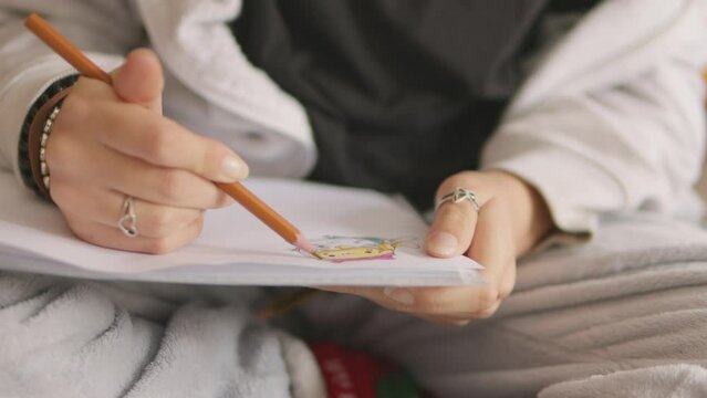 Art of young student girl drawing in notebook close-up indoors. talented artist draws contours of image. beautiful freelancer girl on sofa draws with pencil in notebook