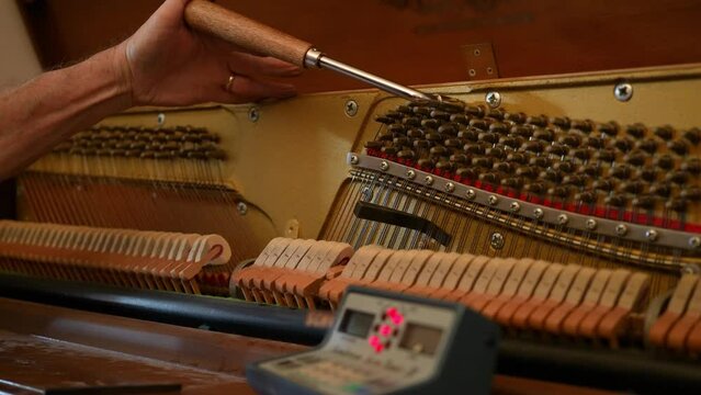 A piano tuner works on an upright piano.  	