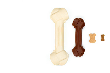 Top view of four types of dog treats: large white bone, medium red bone, cookie bone, small bone on a white background. Dog food concept.