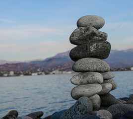 Balance pebble stone in the stoned beach at sunset. Stack of zen stones in harmony and balance with sea view. minimalist view of  stacked arrangement of pebbles on serene beach. mountain on background