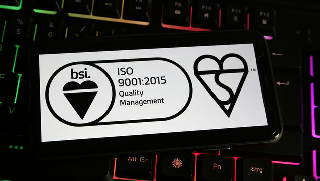 Viersen, Germany - January 9. 2024: Closeup of mobile phone with logo lettering of BSI group quality management label on computer keyboard