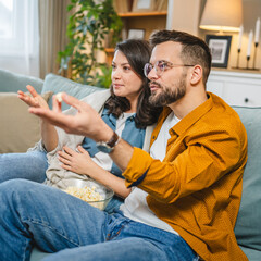 Couple caucasian man and woman sit at home on sofa bed watch tv movie