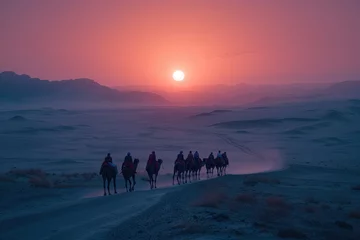 Fototapeten A caravan of camels walking in line on a desert dune under a vibrant sunset sky, leaving footprints in the sand. © Tuannasree