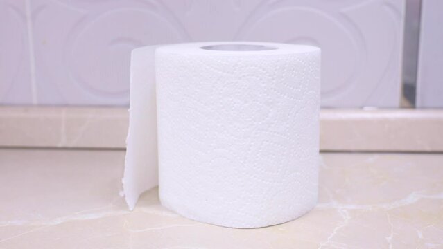 Female hand putting a toilet paper roll on a shelf close up